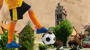 Dziecko gra w piłkę nożną na tle miejskiego krajobrazu.