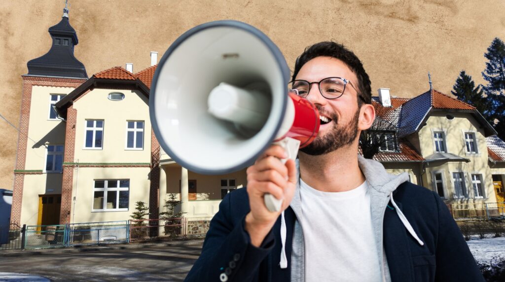 Mężczyzna z megafonem przed budynkiem.