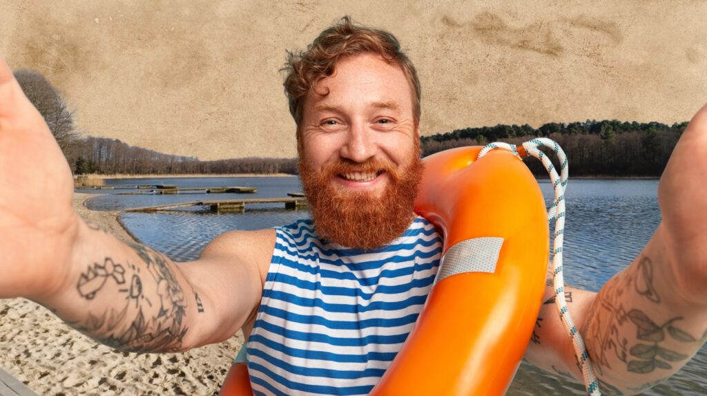 Mężczyzna z czerwoną brodą trzyma koło ratunkowe nad jezorem.