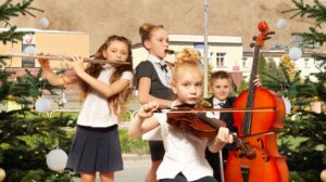 Czwórka dzieci grających na instrumentach muzycznych przy choince.