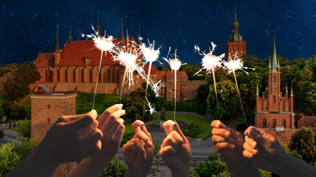 Wielu ludzi trzyma raczki świetlne z zarysem zamku w tle.