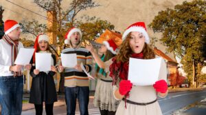 Grupa ludzi śpiewających w strojach świątecznych.