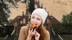 Młoda kobieta trzyma muffin na tle budynku.