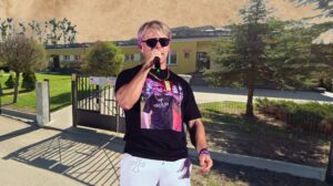 Mężczyzna z mikrofonem na tle budynku.