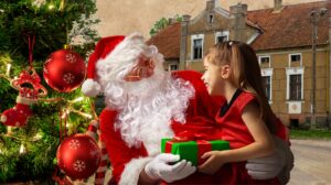 Święty Mikołaj wręcza prezent dziewczynce.