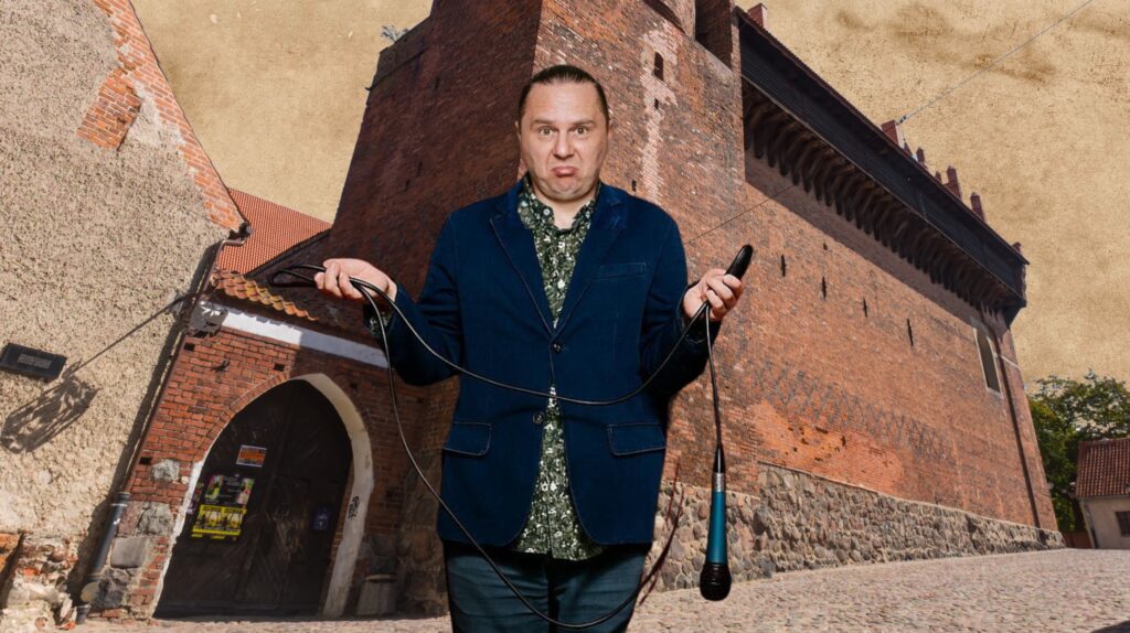 Mężczyzna trzyma mikrofon i przewód w rękach, na tle zamku.