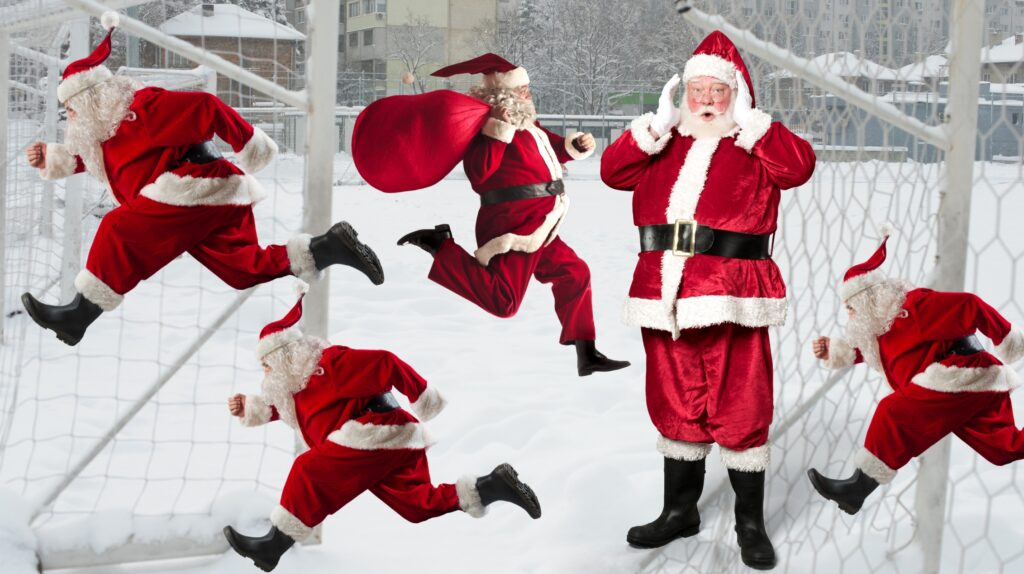 Grupa Mikołajów biegnących na boisku w śniegu.