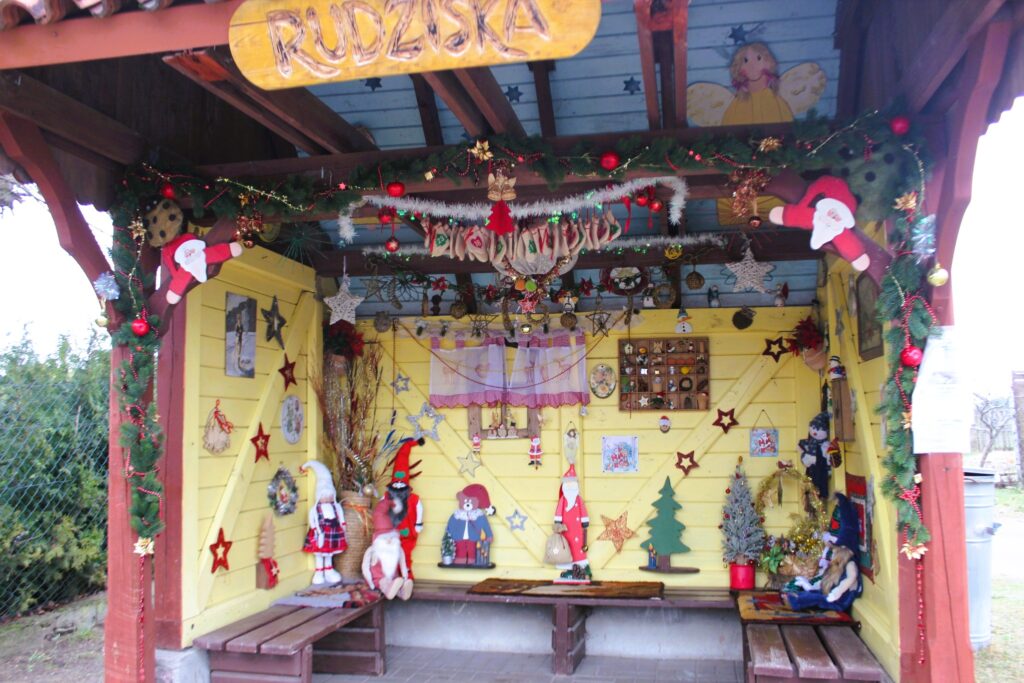 Dekoracyjny kącik w żółtej altanie ozdobiony świątecznymi elementami.