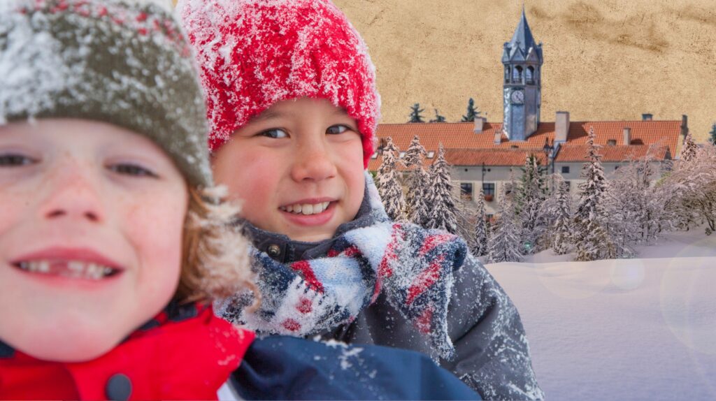 Dwoje dzieci w zimowych czapkach na tle zaśnieżonego krajobrazu.