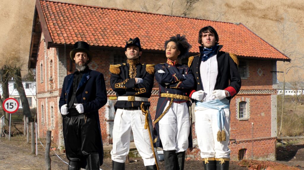 Grupa ludzi w historycznych strojach, pozująca przed budynkiem.