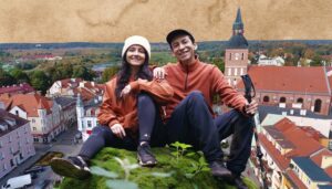 Para w odzieży turystycznej siedzi na wzgórzu z widokiem na miasto.