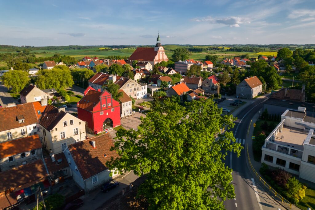 Widok na malownicze miasteczko z czerwonym budynkiem i zielonymi drzewami.