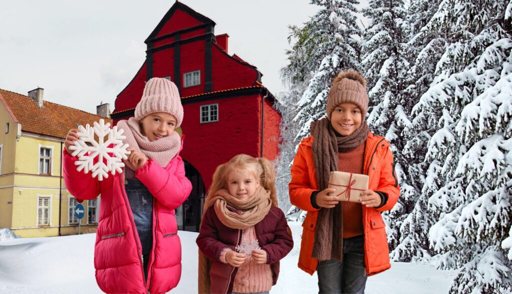 Dzieci w zimowych kurtkach trzymają śnieżynki i prezent.