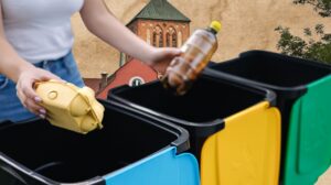 Osoba segregująca odpady do kolorowych pojemników.
