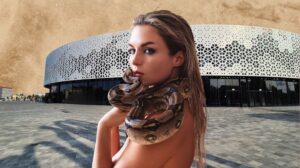 Kobieta z wężem na ramieniu w nowoczesnej architekturze.