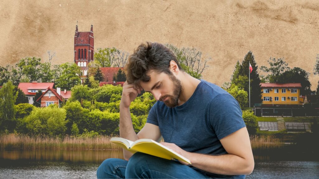 Mężczyzna czytający książkę nad jeziorem.