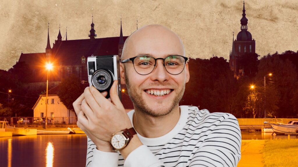 Mężczyzna trzyma aparat fotograficzny w ręku.