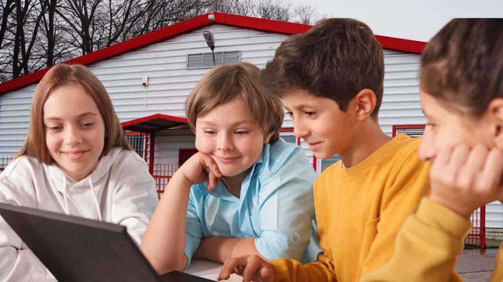 Czwórka dzieci oglądających tablet przed budynkiem.