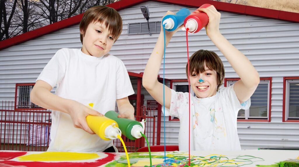 Dzieci malują farbami na stole.