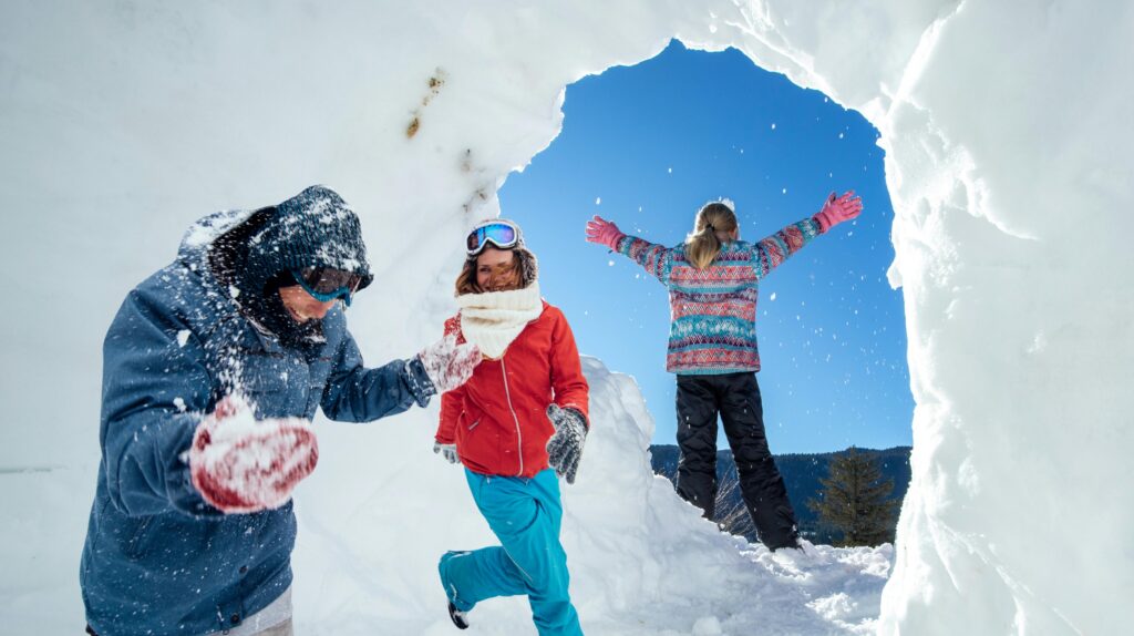Dzieci bawią się w śniegu na tle niebieskiego nieba.