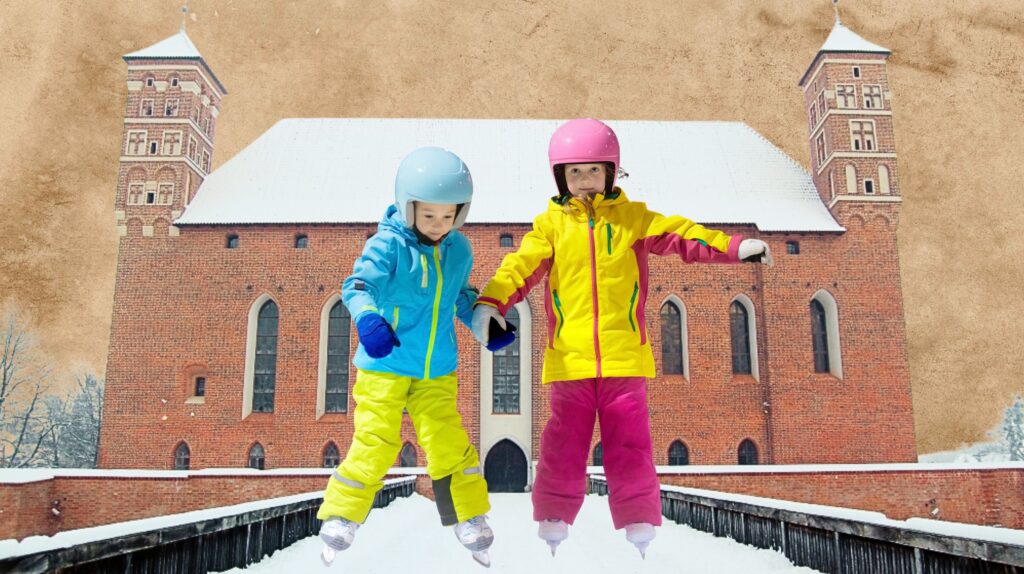 Dzieci w kolorowych kurtkach ślizgają się na łyżwach na tle zabytkowego budynku.