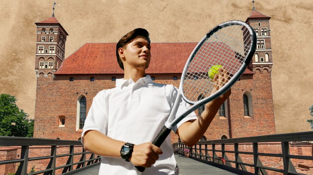 Mężczyzna trzyma rakietę tenisową z piłką w tle historyczny budynek.