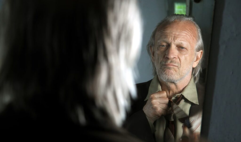 Mężczyzna w lustrze poprawiający krawat.