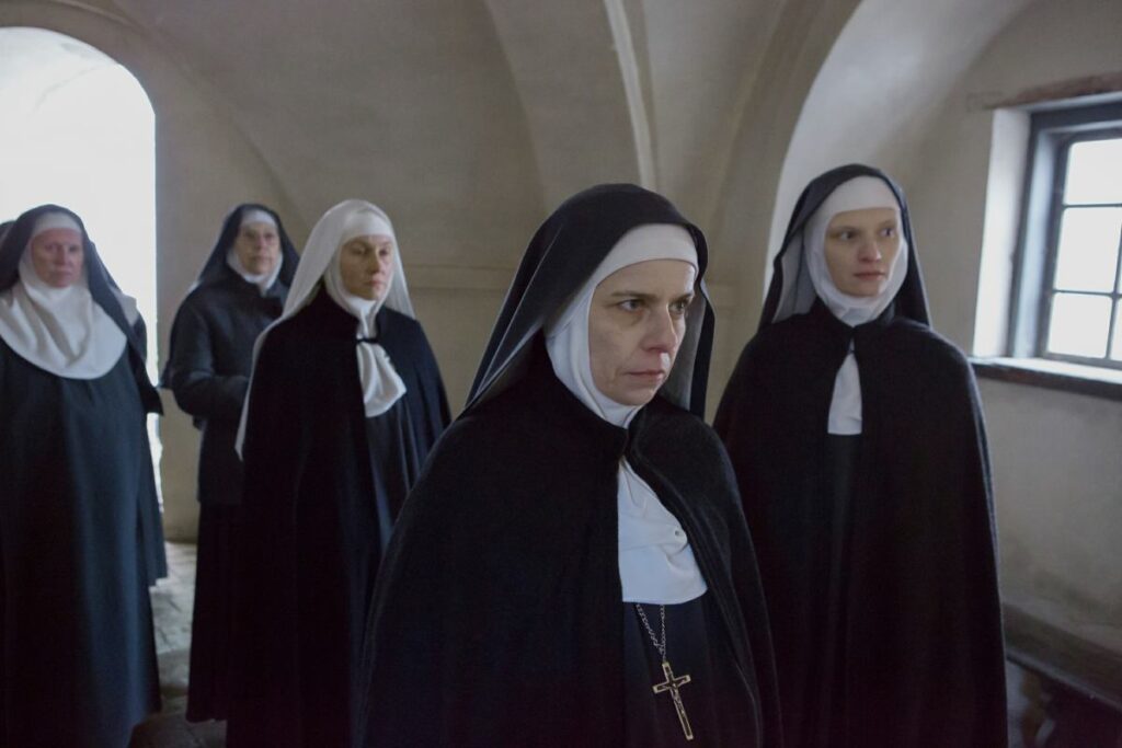 Grupa zakonnic w ciemnym pomieszczeniu.