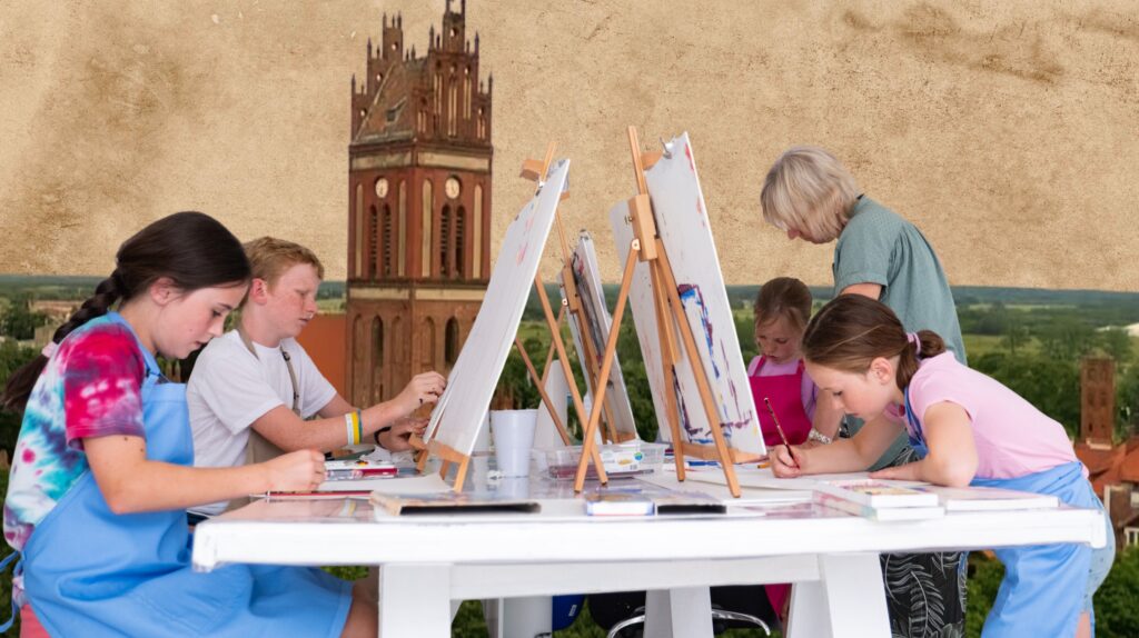 Grupa dzieci malujących obrazy na zajęciach artystycznych.