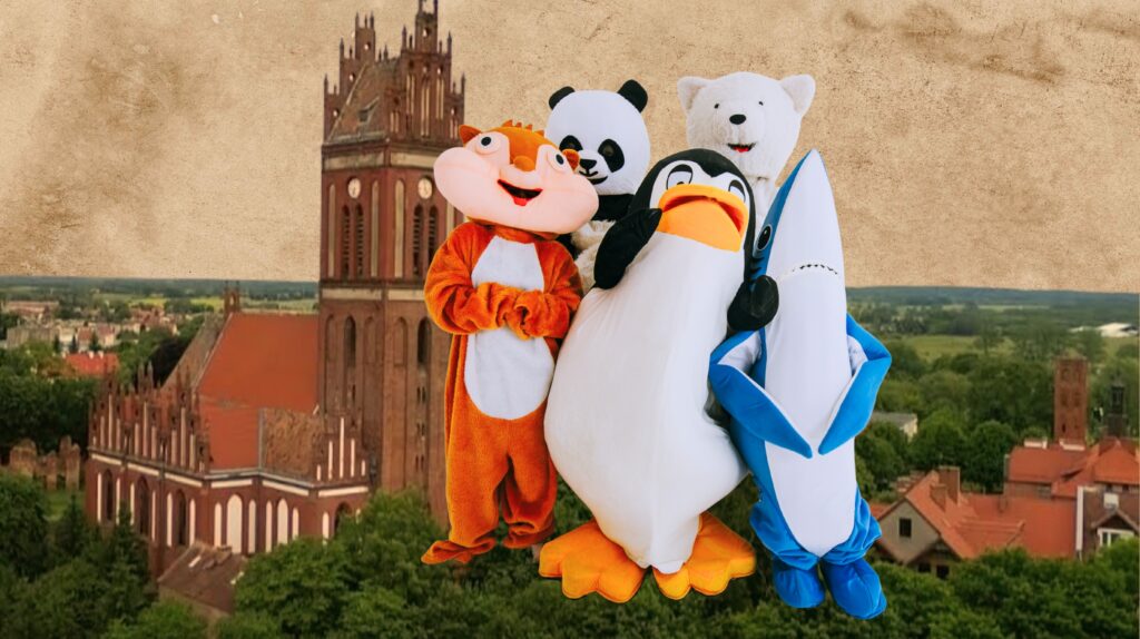 Cztery postacie w kostiumach zwierząt przy zabytkowym budynku.