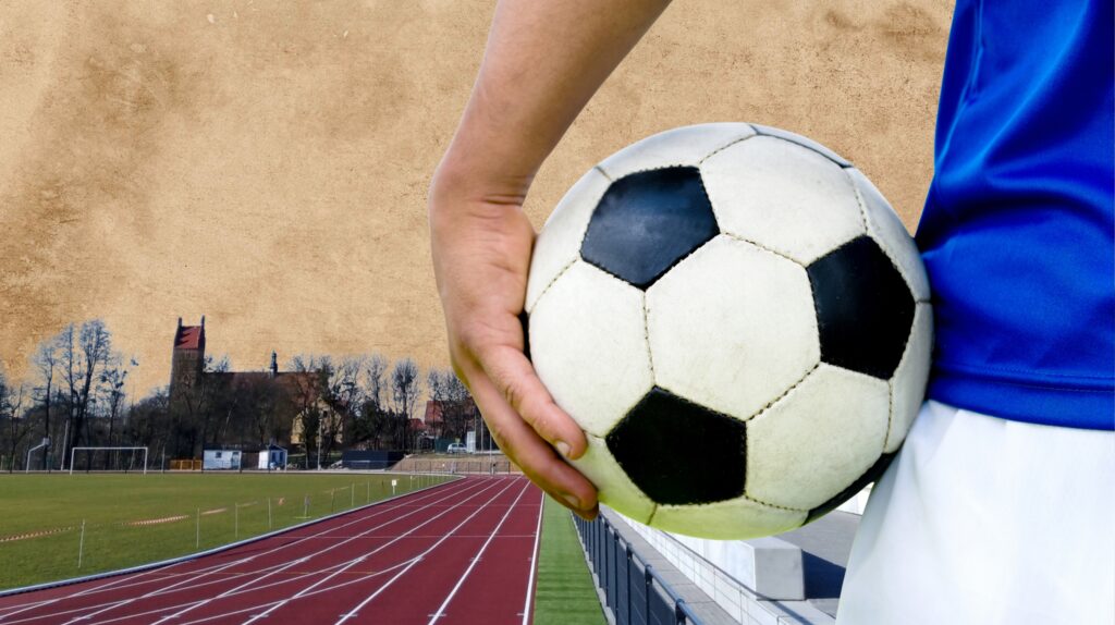 Osoba trzymająca piłkę nożną na stadionie.