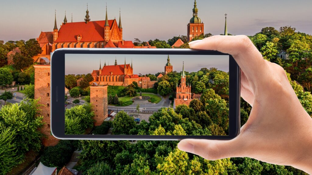 Widok z telefonu na zamek i zielony krajobraz.