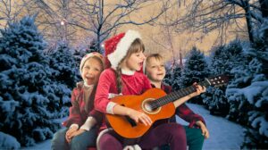 Dzieci śpiewają i grają na gitarze w zimowym otoczeniu.