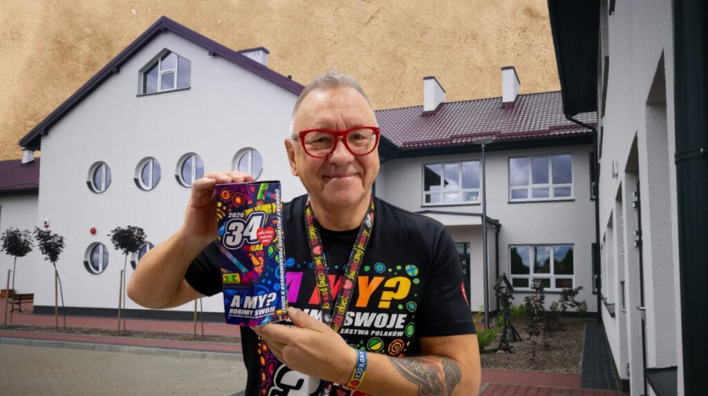 Mężczyzna trzymający kolorową książkę przed budynkiem.