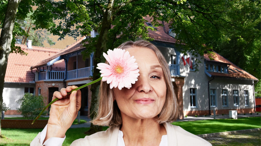 Kobieta z różową kwiatem na twarzy w ogrodzie.