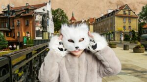 Dziecko w maski kota na tle miasta.