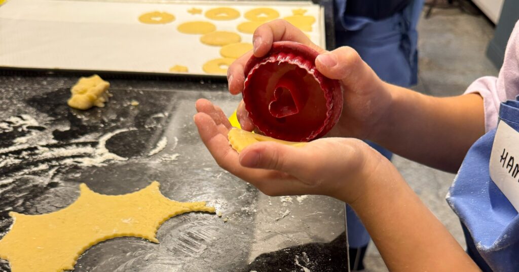 Osoba trzymająca foremki do ciastek w kuchni.