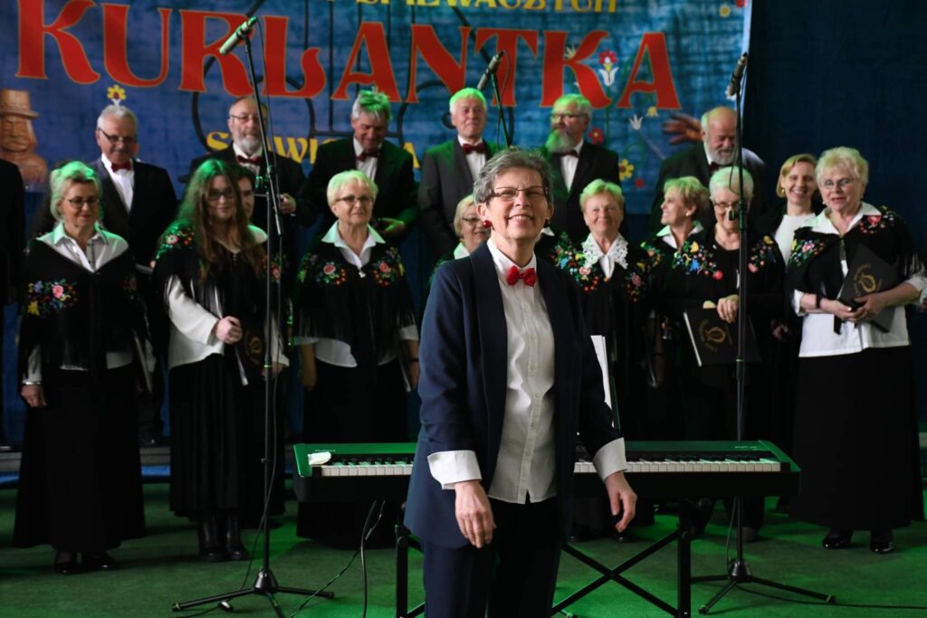 Chór występujący na scenie z pianistą.