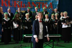 Chór występujący na scenie z pianistą.