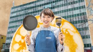 Uśmiechnięta osoba trzyma patelnię i łopatkę.