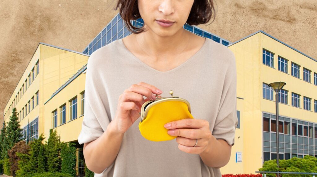 Kobieta trzyma żółty portfel w tle budynku.