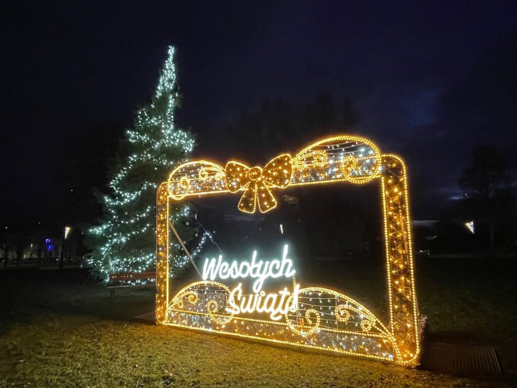 Oświetlony napis 'Wesołych Świąt' w parku.