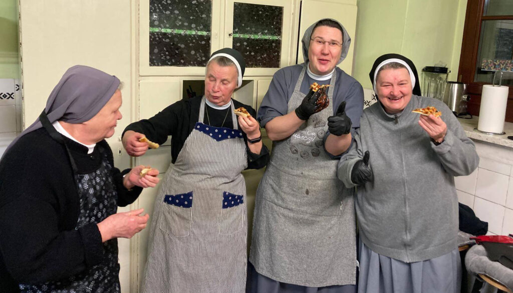 Cztery siostry zakonne cieszą się jedzeniem w kuchni.