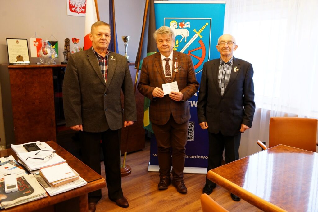 Trzech mężczyzn pozujących w biurze z dokumentami