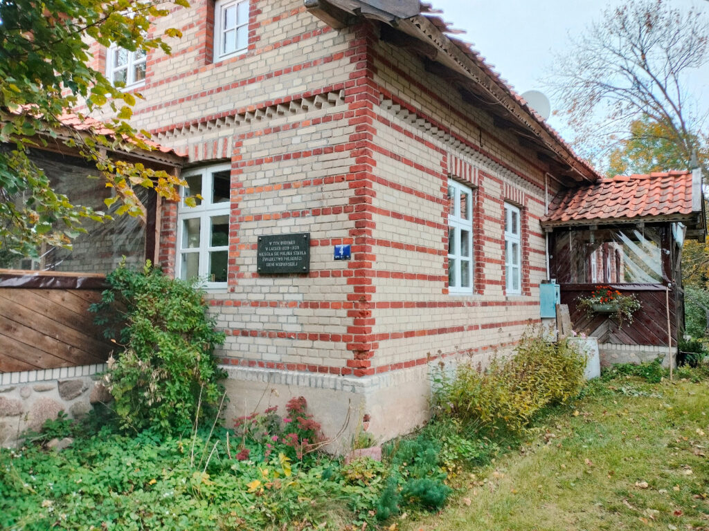 Ceglany dom z zielenią wokół.