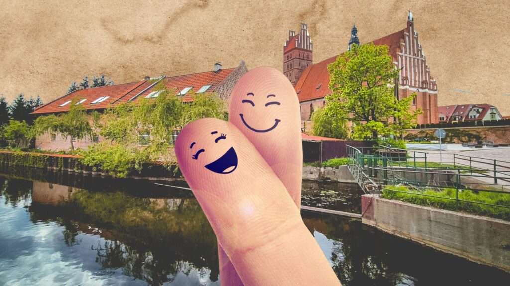 Dwa palce z uśmiechami na tle architektury i wody.