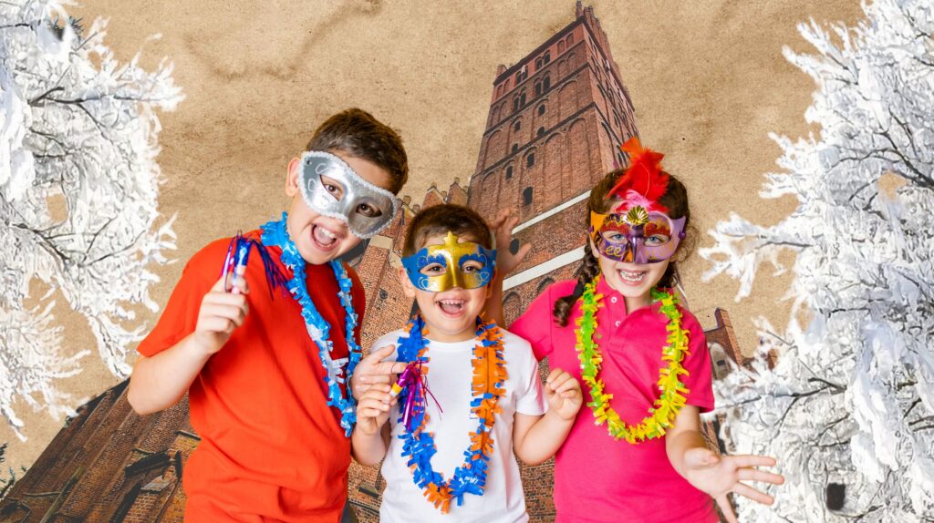 Dzieci w maskach i kolorowych naszyjnikach, pozujące z radosnymi minami.