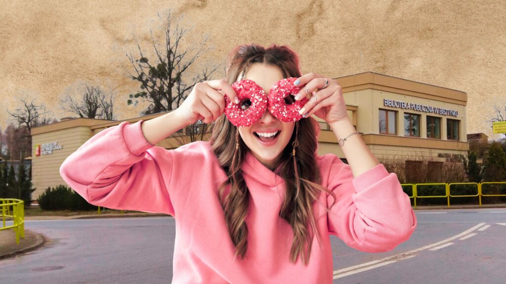 Uśmiechnięta dziewczyna trzyma dwa różowe pączki.