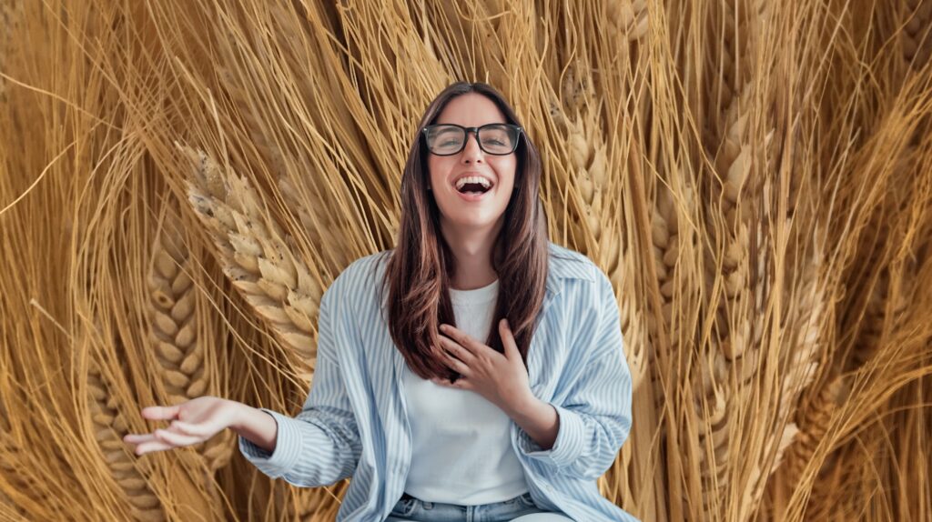 Uśmiechnięta kobieta wśród kłosów zbóż.