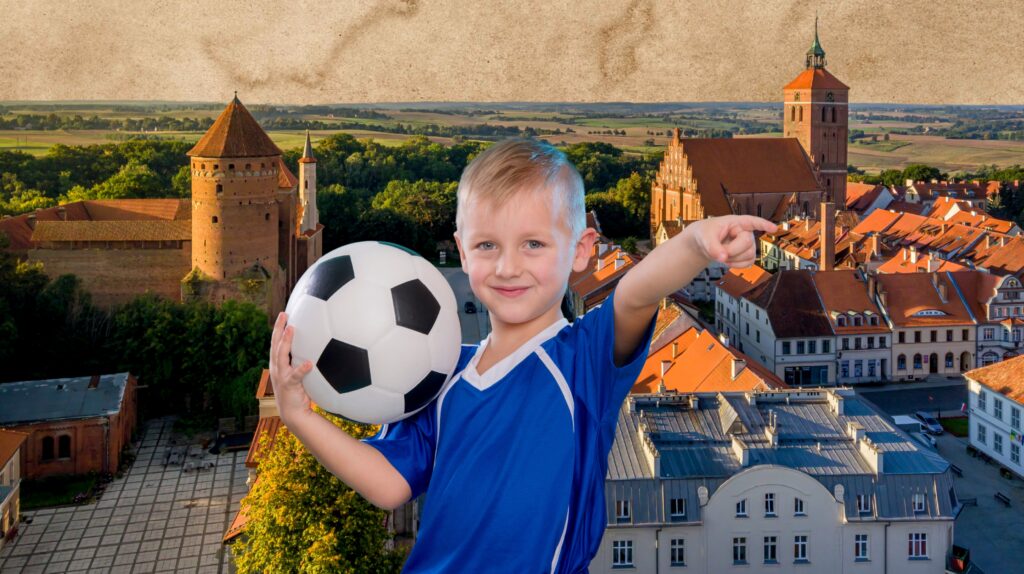 Chłopiec trzymający piłkę nożną z widokiem na miasto i zamek.